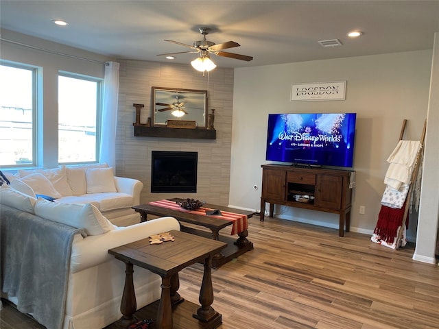 living room featuring hardwood / wood-style flooring, ceiling fan, and a fireplace