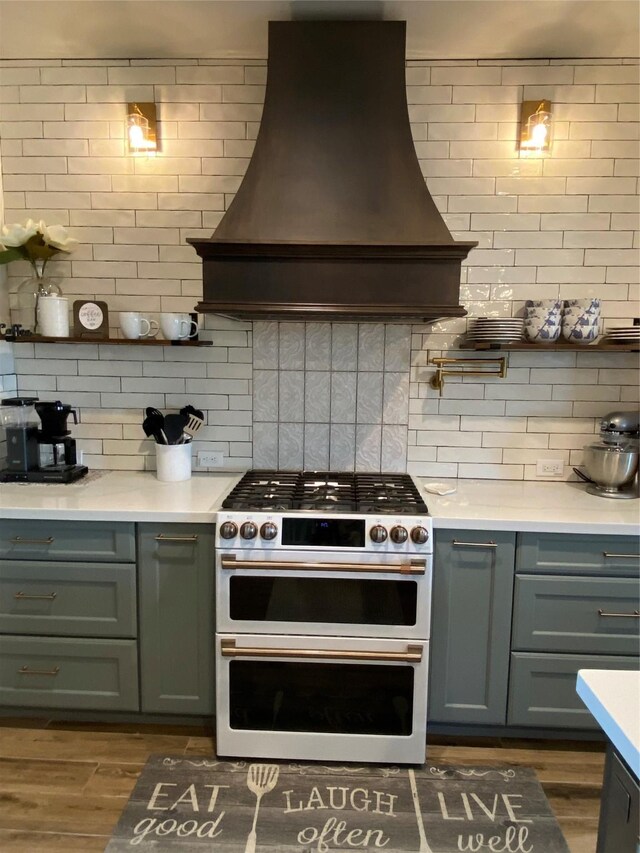 kitchen with double oven range, decorative backsplash, dark wood-type flooring, and custom range hood