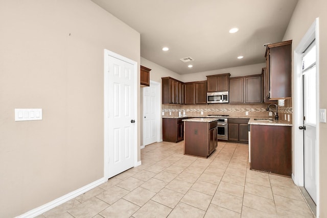 kitchen featuring sink, decorative backsplash, a center island, stainless steel appliances, and dark brown cabinets