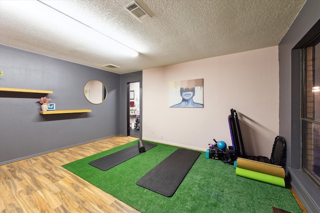 workout room with golf simulator, hardwood / wood-style floors, and a textured ceiling