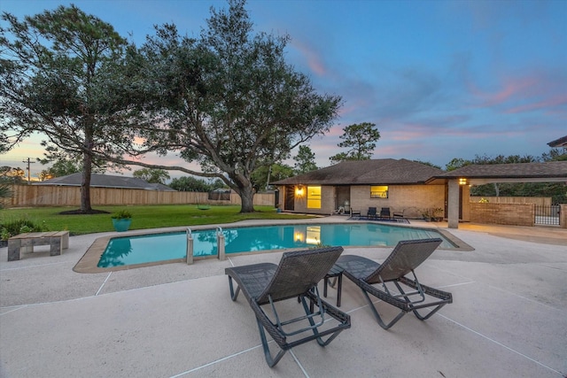 pool at dusk with a yard and a patio