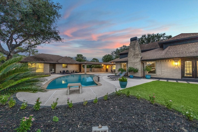 pool at dusk featuring a yard and a patio area