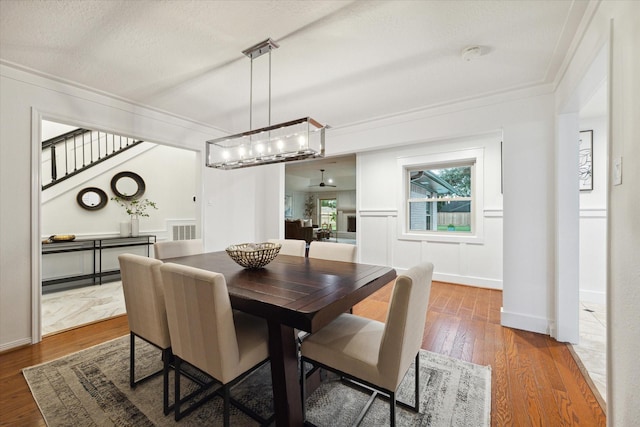 dining space with ornamental molding, hardwood / wood-style floors, and a textured ceiling