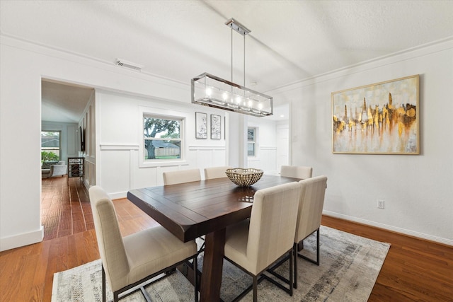 dining area featuring dark wood-type flooring, crown molding, and a wealth of natural light