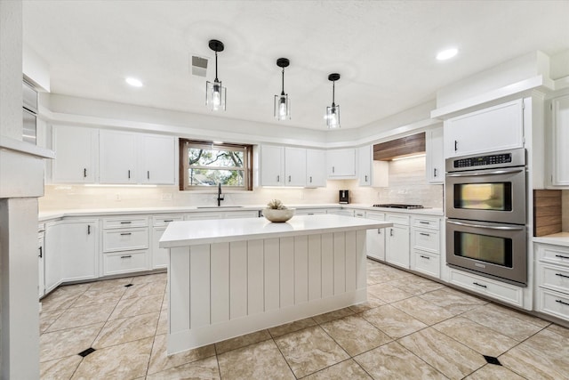 kitchen with a kitchen island, pendant lighting, double oven, sink, and black gas stovetop