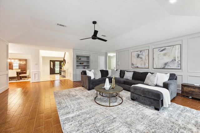 living room with hardwood / wood-style flooring, lofted ceiling, ceiling fan, and built in shelves