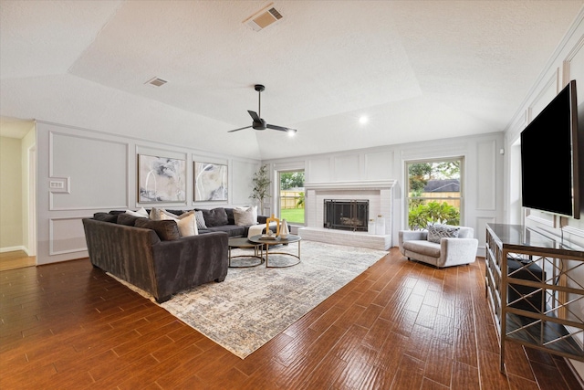 living room featuring lofted ceiling, dark hardwood / wood-style floors, a fireplace, and a raised ceiling