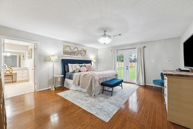 bedroom with hardwood / wood-style flooring, access to exterior, ensuite bath, and french doors