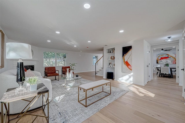 living room featuring light wood-type flooring and built in shelves