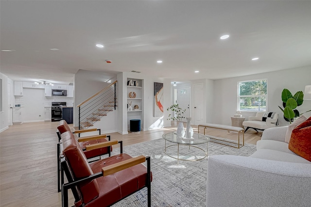 living room featuring built in features and light wood-type flooring