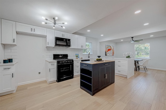 kitchen with black appliances, a kitchen island, white cabinets, light hardwood / wood-style floors, and backsplash