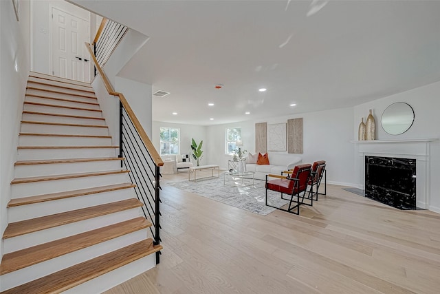 stairs with hardwood / wood-style flooring and a premium fireplace