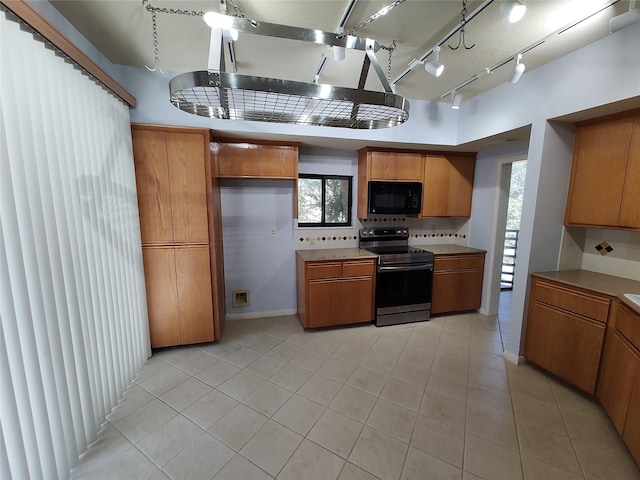 kitchen featuring tasteful backsplash, light tile patterned floors, and stainless steel range with electric cooktop