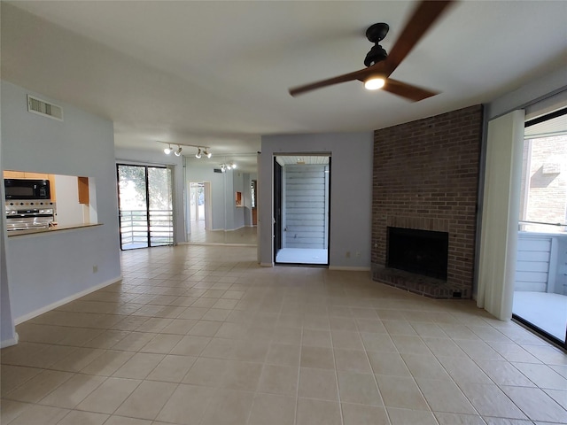 unfurnished living room with ceiling fan, plenty of natural light, a fireplace, and light tile patterned floors