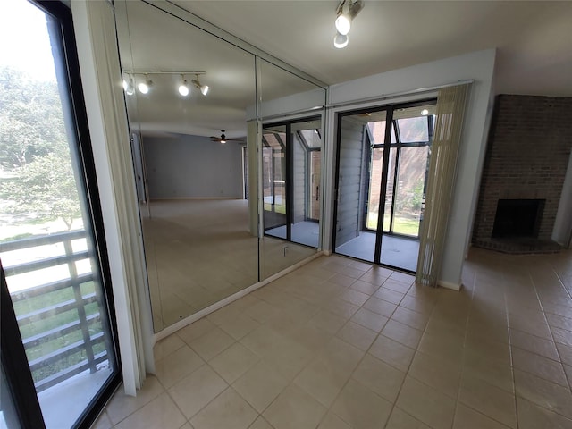 interior space with light tile patterned floors, a fireplace, and ceiling fan