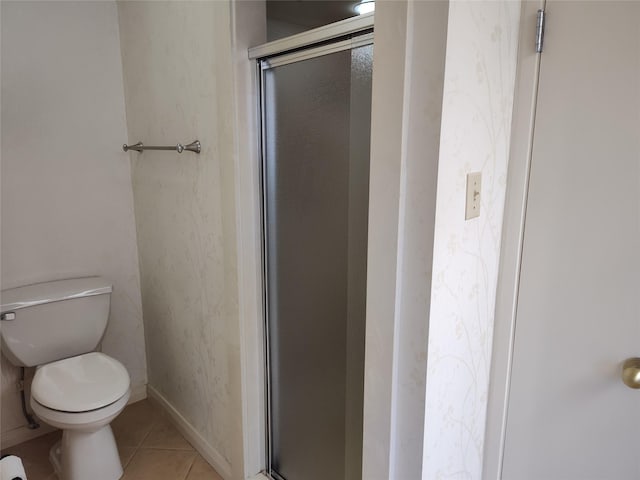 bathroom with tile patterned floors, toilet, and a shower with door