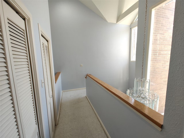 hallway with lofted ceiling and light carpet