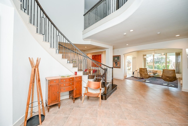 stairs with crown molding and a high ceiling