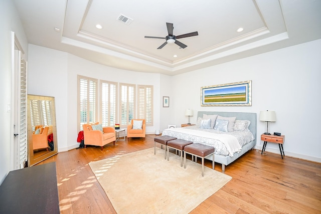 bedroom with crown molding, ceiling fan, a raised ceiling, and light hardwood / wood-style flooring