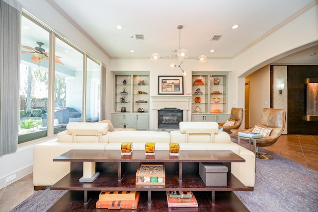 living room featuring crown molding, ceiling fan with notable chandelier, built in features, and tile patterned floors