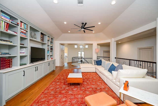 living room with ceiling fan, lofted ceiling, built in features, and light wood-type flooring