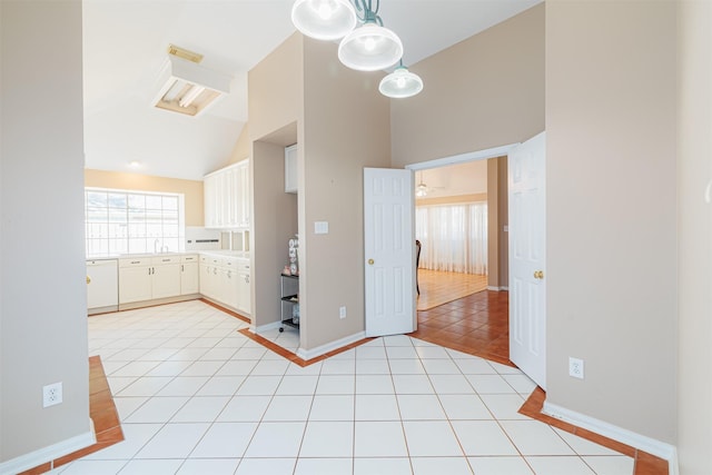 kitchen featuring pendant lighting, light tile patterned floors, lofted ceiling, white dishwasher, and white cabinets