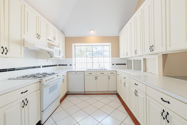 kitchen with vaulted ceiling, sink, light tile patterned floors, kitchen peninsula, and white appliances