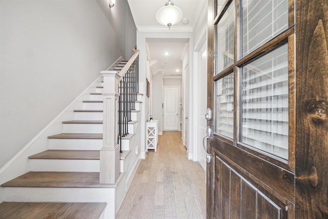 foyer entrance with crown molding and light wood-type flooring