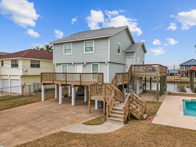 rear view of property with a deck with water view and a patio area