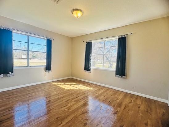 empty room with hardwood / wood-style floors and a wealth of natural light