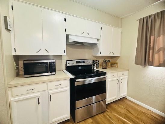 kitchen featuring hardwood / wood-style flooring, appliances with stainless steel finishes, and white cabinets