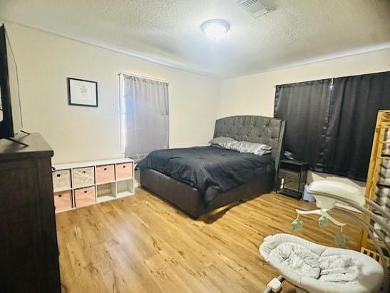 bedroom featuring a textured ceiling and light hardwood / wood-style flooring