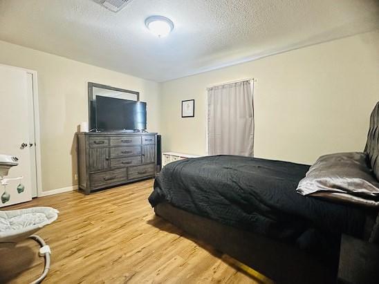 bedroom with light hardwood / wood-style floors and a textured ceiling