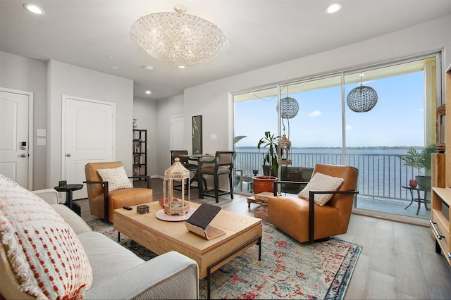 living room featuring a water view, a notable chandelier, and light hardwood / wood-style flooring