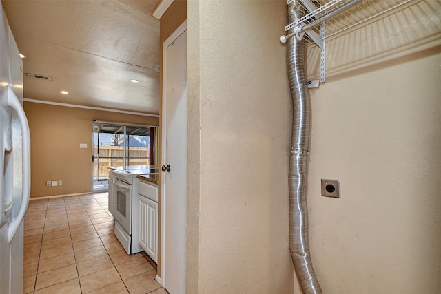 interior space featuring light tile patterned flooring, white appliances, ornamental molding, and white cabinetry