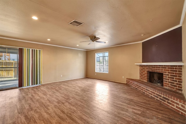 unfurnished living room with hardwood / wood-style flooring, crown molding, ceiling fan, and a fireplace