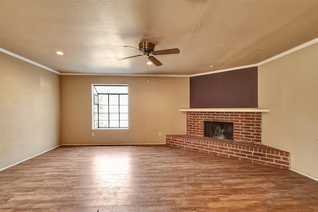 unfurnished living room featuring wood-type flooring, ornamental molding, ceiling fan, a brick fireplace, and a textured ceiling