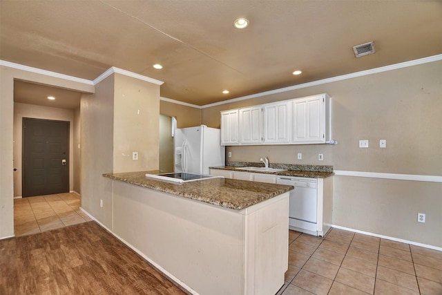 kitchen with sink, dark stone countertops, kitchen peninsula, white appliances, and white cabinets