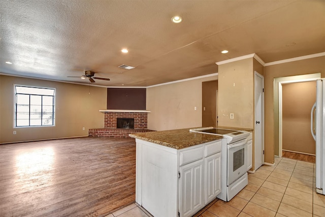 kitchen featuring light tile patterned floors, white appliances, crown molding, white cabinetry, and a brick fireplace