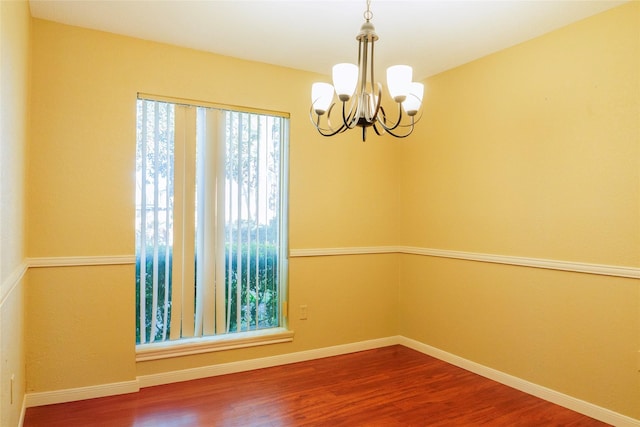 empty room with wood-type flooring and a chandelier