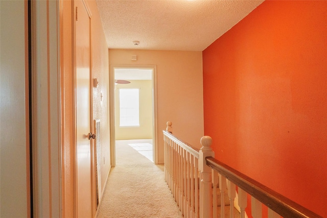 corridor with light colored carpet and a textured ceiling