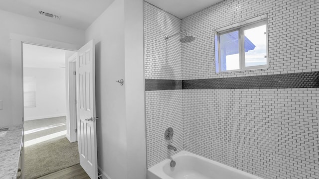 bathroom with tiled shower / bath combo and hardwood / wood-style flooring