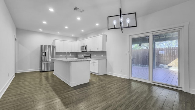 kitchen featuring appliances with stainless steel finishes, decorative light fixtures, white cabinetry, sink, and a kitchen island with sink