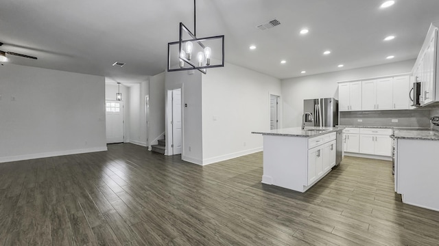 kitchen featuring white cabinetry, a center island with sink, appliances with stainless steel finishes, dark hardwood / wood-style floors, and pendant lighting