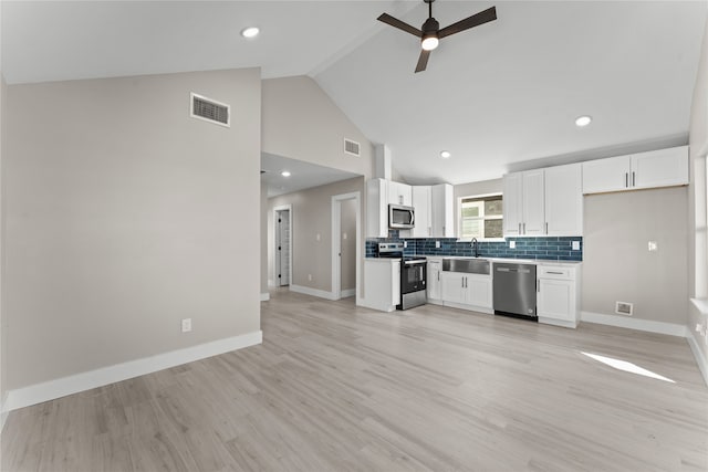 kitchen with sink, high vaulted ceiling, appliances with stainless steel finishes, white cabinets, and backsplash