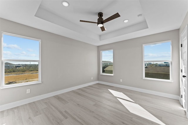 unfurnished room featuring a tray ceiling, light hardwood / wood-style floors, and ceiling fan