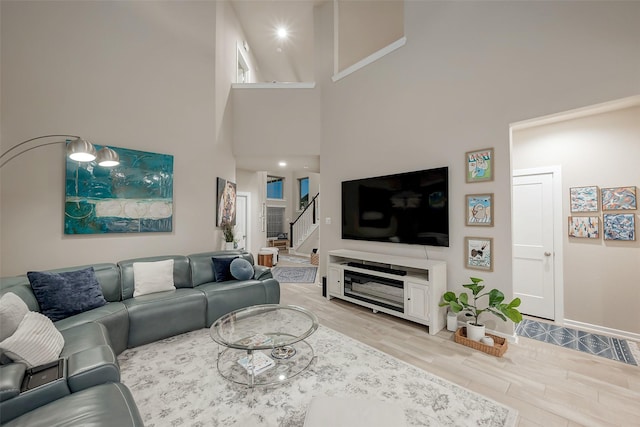 living room featuring a towering ceiling and light hardwood / wood-style flooring