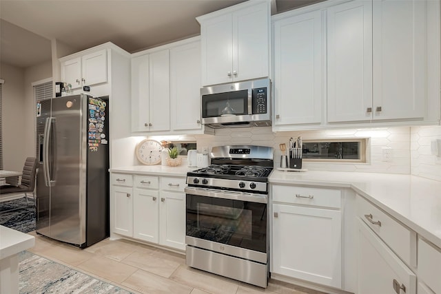 kitchen featuring tasteful backsplash, appliances with stainless steel finishes, light tile patterned floors, and white cabinets