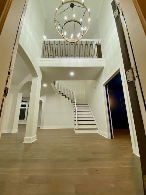 interior space featuring an inviting chandelier, a towering ceiling, and wood-type flooring