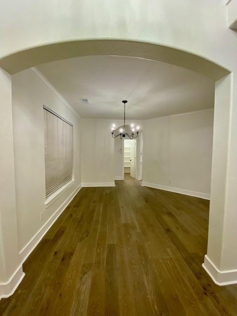 unfurnished dining area featuring crown molding, dark hardwood / wood-style flooring, and a notable chandelier